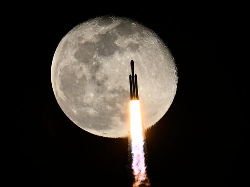 SpaceX-Rakete nach dem Start, im Hintergrund ist der Mond zu sehen. SpaceX-Rakete nach dem Start, im Hintergrund ist der Mond zu sehen.