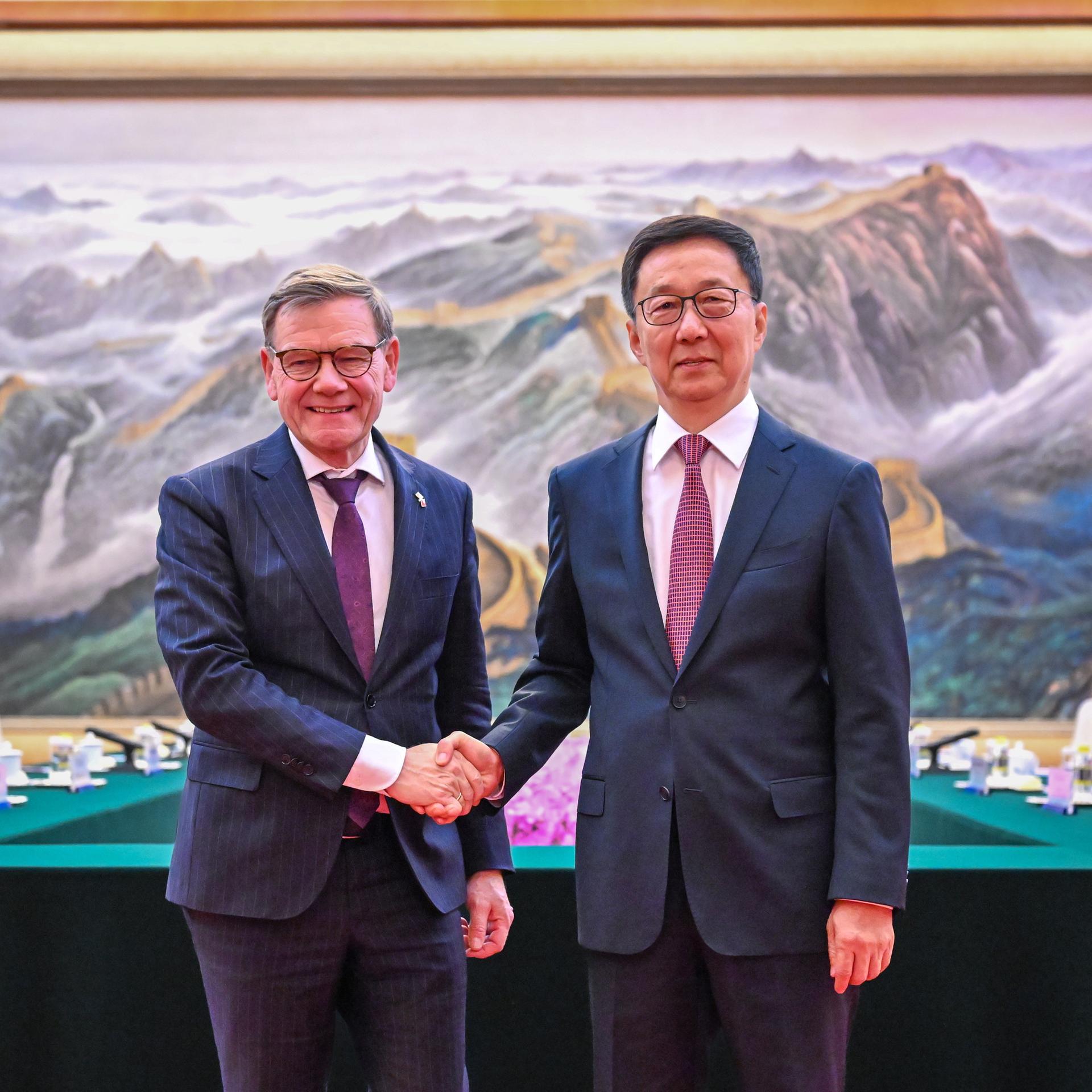 Peking: Bundesaußenminister Johann Wadephul (l, CDU) wird von Han Zheng, stellvertretender Präsident der Volksrepublik China, vor einem überdimensionalen Gemälde, dass die chinesische Mauer zeigt, begrüßt. 