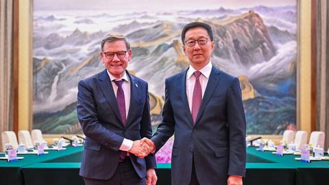 Peking: Bundesaußenminister Johann Wadephul (l, CDU) wird von Han Zheng, stellvertretender Präsident der Volksrepublik China, vor einem überdimensionalen Gemälde, dass die chinesische Mauer zeigt, begrüßt. 