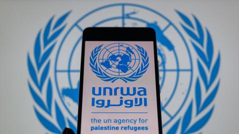 Das Logo des UN-Palästinenser-Hilfswerks UNRWA ist auf einem Handy zu sehen.