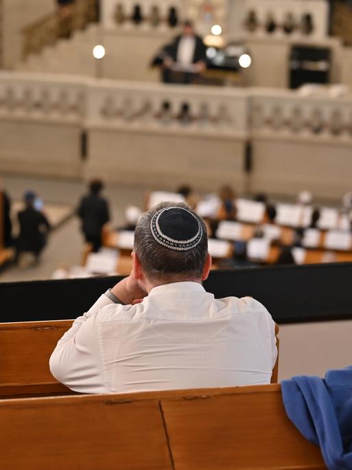 Ein Mann mit Kippa sitzt auf der Empore der Synagoge Rykestraße in Berlin und schaut hinunter auf eine Ordinationszeremonie.