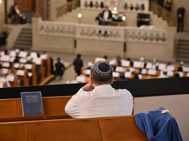Ein Mann mit Kippa sitzt auf der Empore der Synagoge Rykestraße in Berlin und schaut hinunter auf eine Ordinationszeremonie.