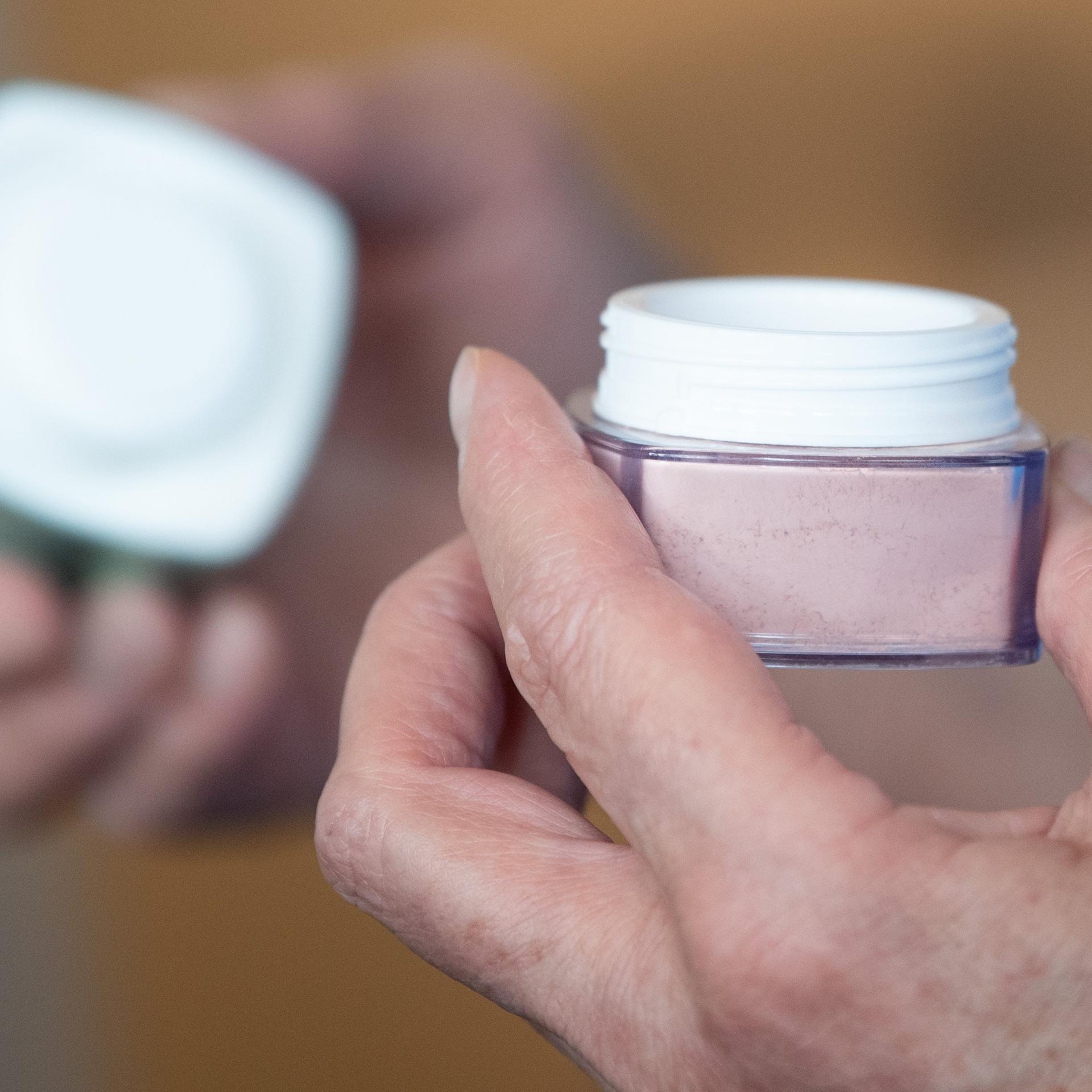 Sachsen, Dresden: Eine Teilnehmerin hält im Universitätsklinikum Carl Gustav Carus Dresden während eines Kosmetikseminars von DKMS Life eine Cremedose in den Händen.