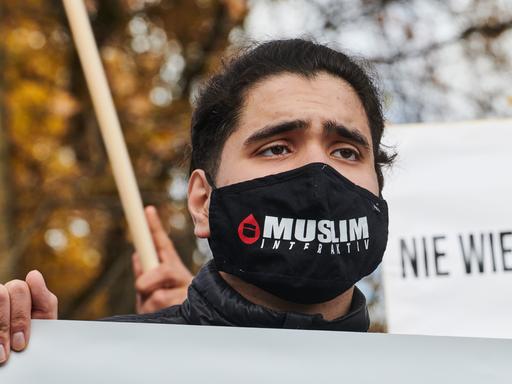 Ein Demonstrant trägt einen Mundschutz auf dem "Muslim Interaktiv" steht.