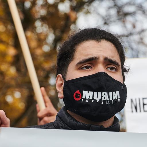 Ein Demonstrant trägt einen Mundschutz auf dem "Muslim Interaktiv" steht.