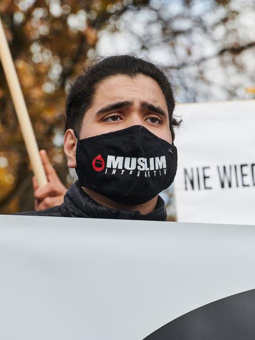 Ein Demonstrant trägt einen Mundschutz auf dem "Muslim Interaktiv" steht.