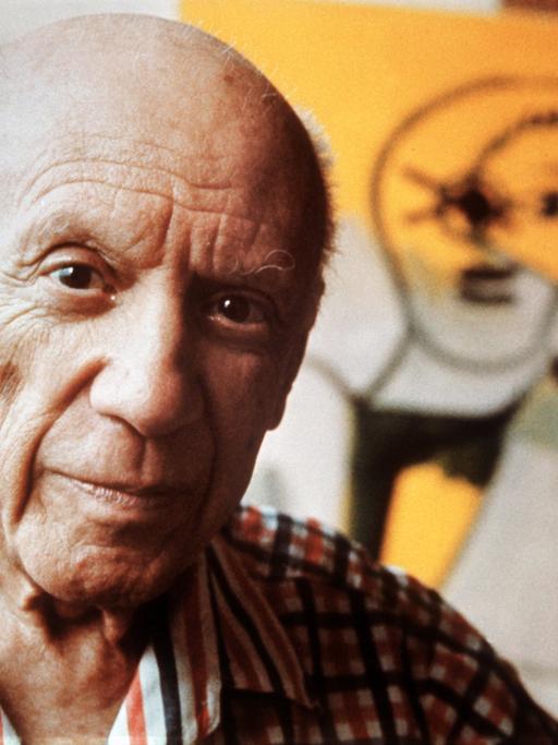 Der Maler Pablo Picasso blickt in die Kamera, im Hintergrund ein Gemälde von ihm. (Quelle: dpa)