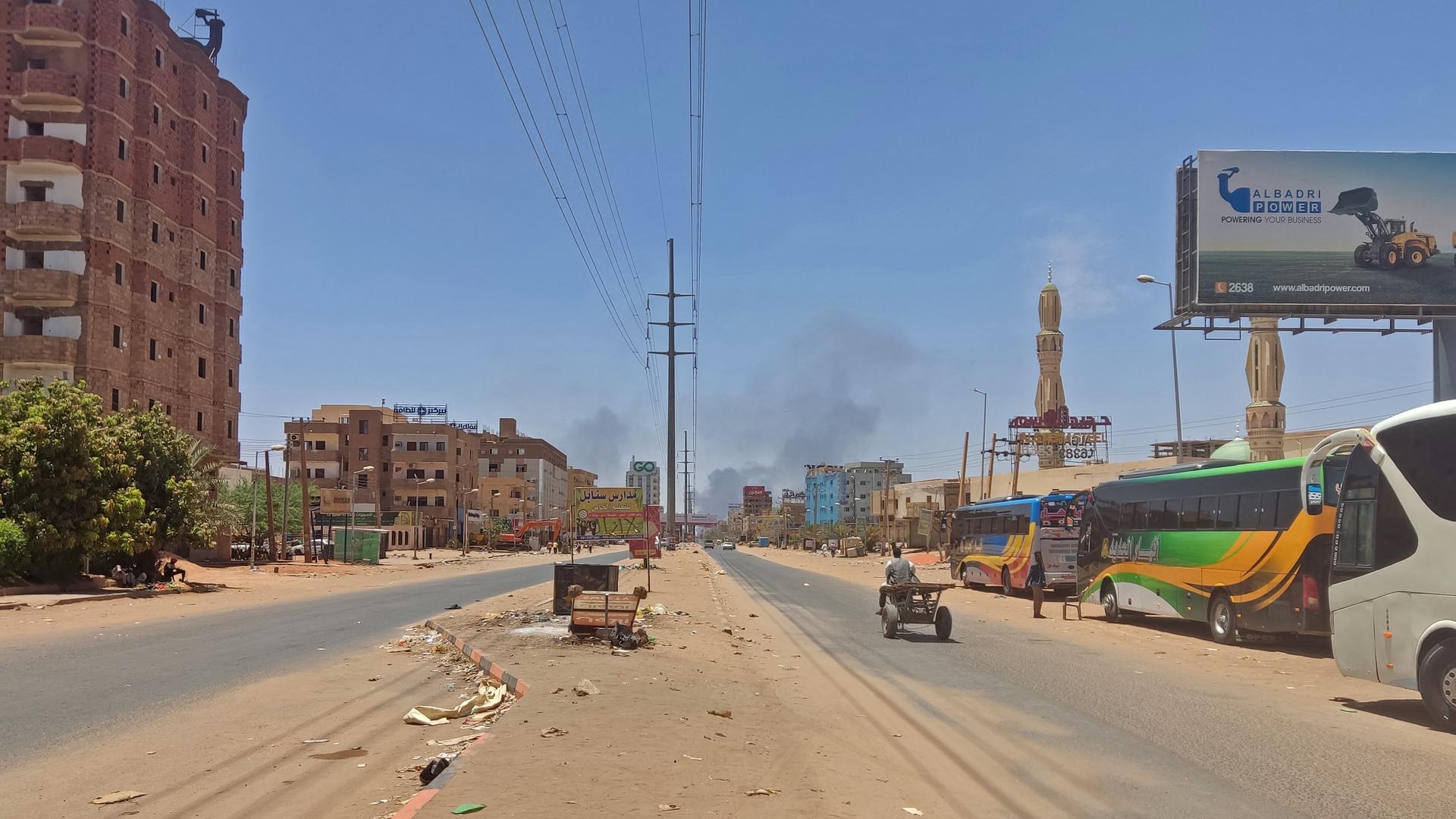 Eine fast leere staubige Straße in Khartum. Am Horizont ist Rauch zu sehen.