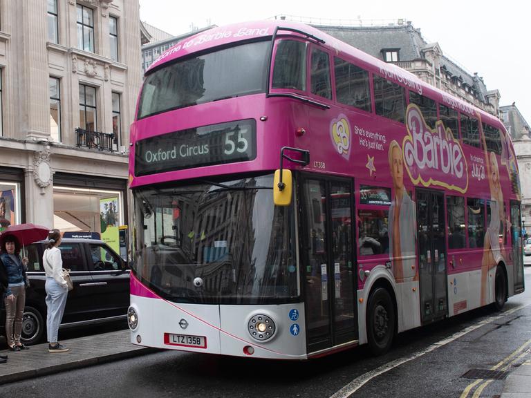 Ein Doppeldecker-Bus in London mit Werbung für den Film "Barbie" in pink. 