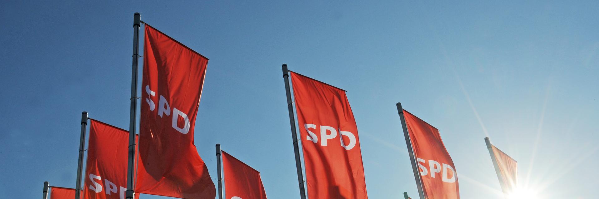 Rote Fahnen mit dem SPD Logo wehen vor einem Landesparteitag.