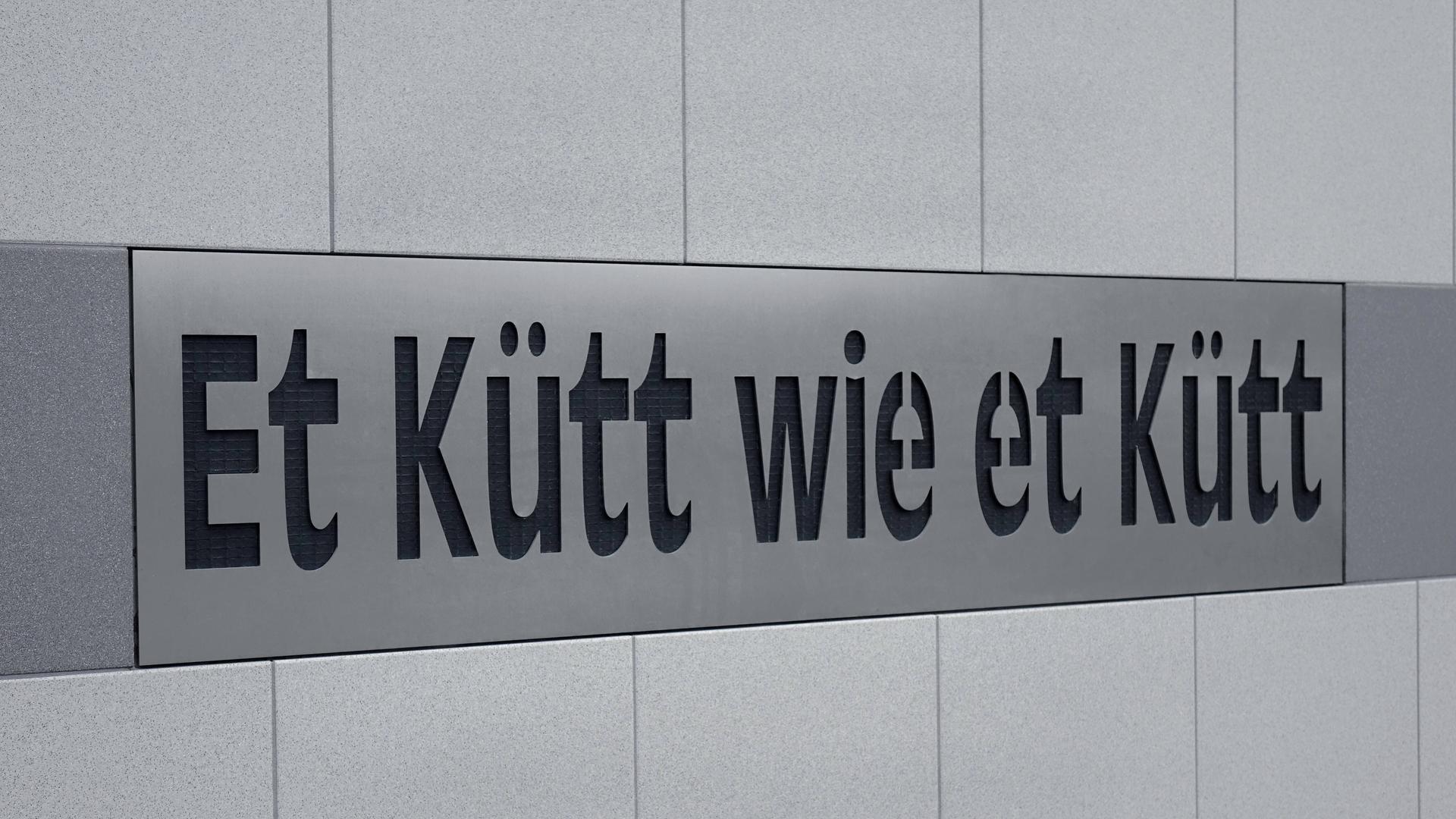 An einem Wohnhaus in Köln steht die Kölsche Redewendung "Et kütt wie et kütt".
