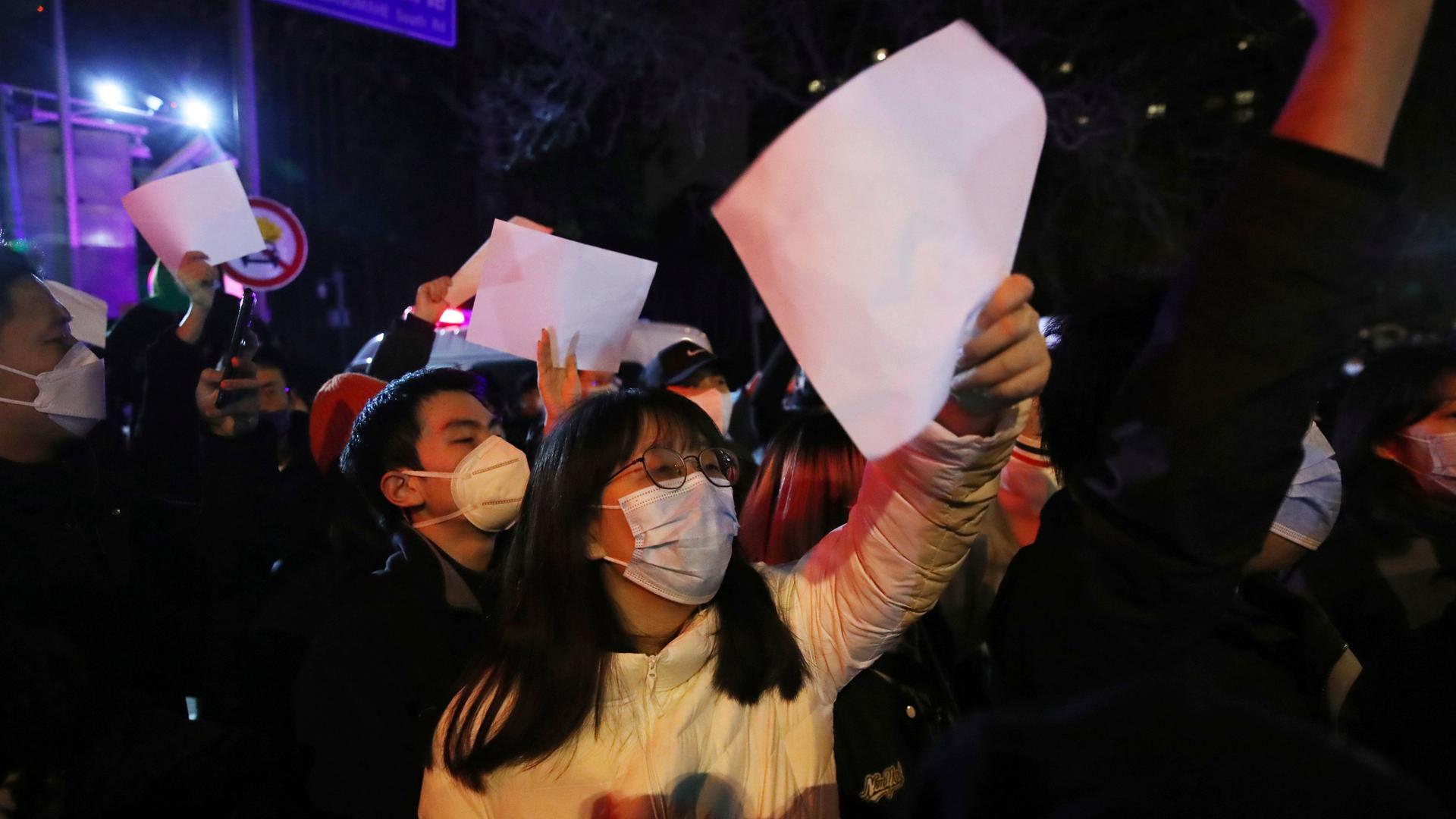 Mehrere Menschen demonstrieren gegen die Null-Covid-Politik in China und halten weiße, unbeschriftete Zettel in die Höhe.