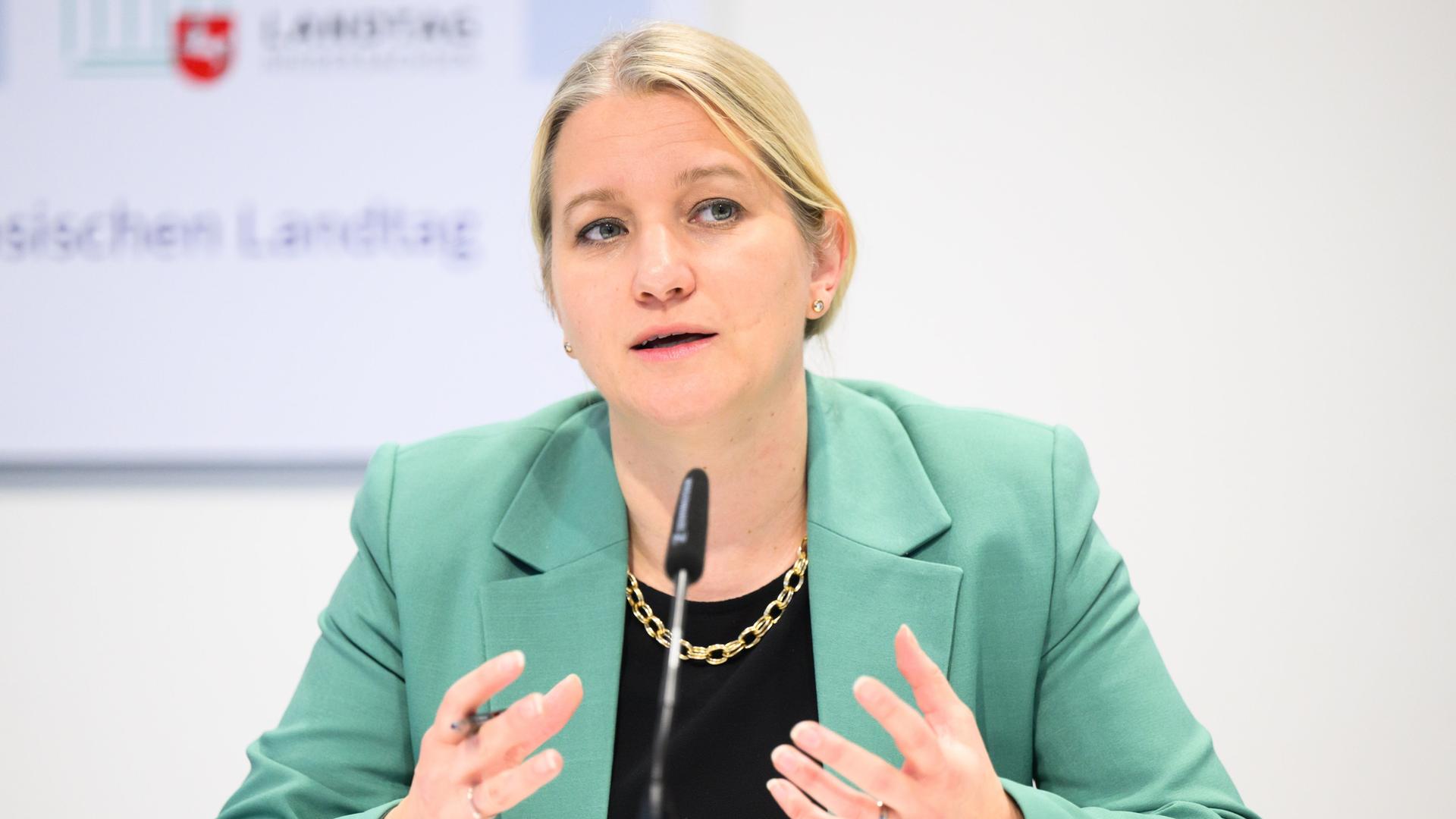 Kathrin Wahlmann, Justizministerin Niedersachsen, sitzt an einem Tisch und spricht in ein Mikrofon. Dabei gestikuliert sie mit den Händen. Kathrin Wahlmann, Justizministerin Niedersachsen, sitzt an einem Tisch und spricht in ein Mikrofon. Dabei gestikuliert sie mit den Händen.