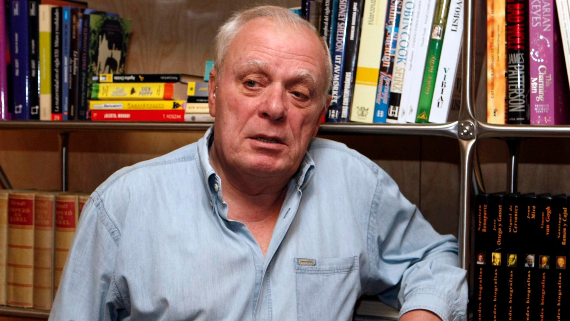 Der portugiesische Schriftsteller Antonio Lobo Antunes steht an ein Bücherregal gelehnt.