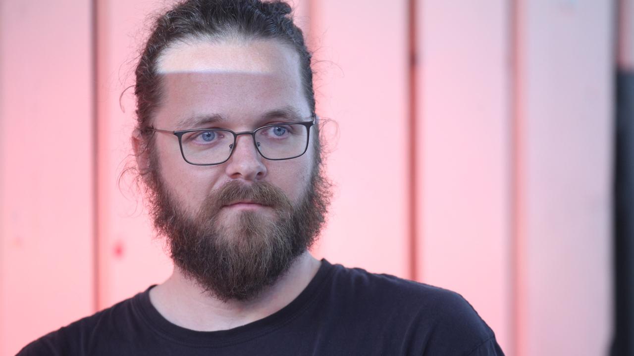 Arne Semsrott mit Vollbart und Brille vor einem rosafarbenen Hintergrund