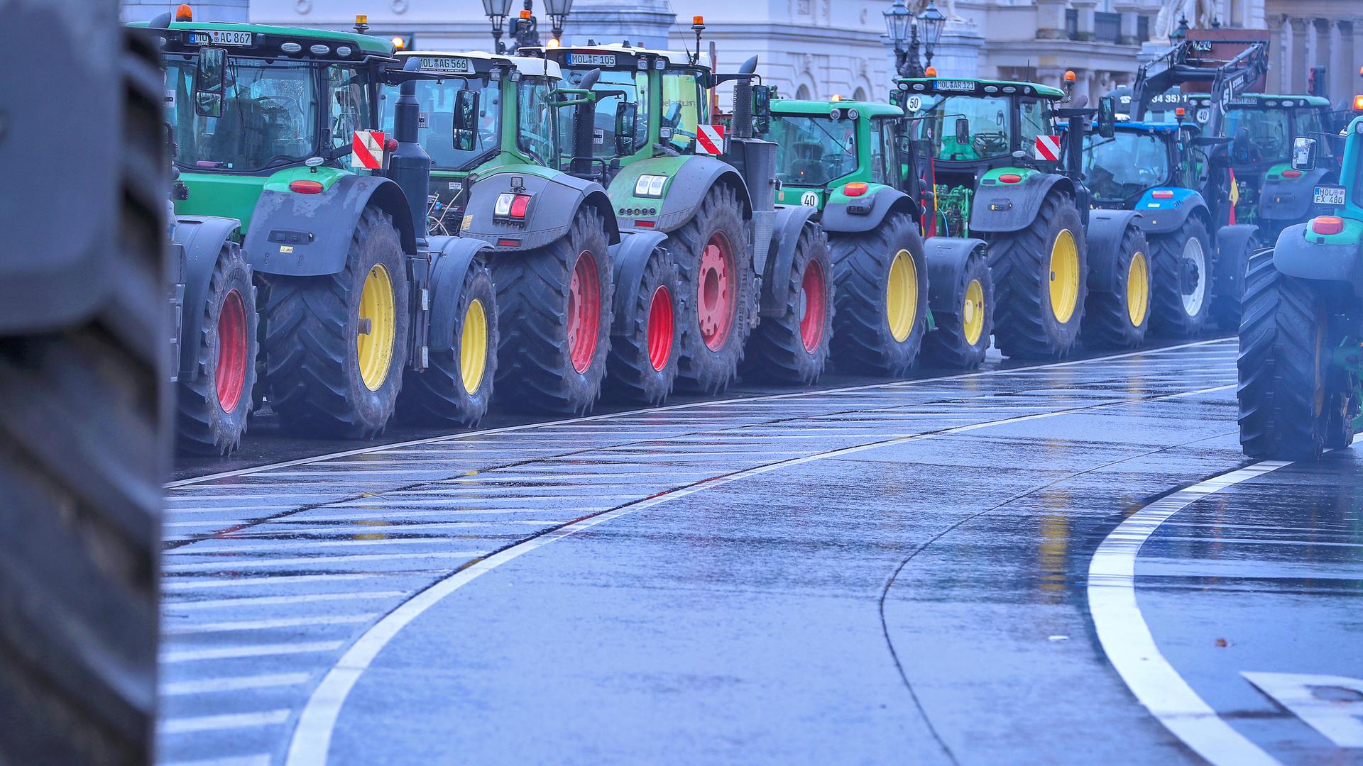 Auf einer Straße in Berlin stehen eine Reihe Traktoren hintereinander und demonstrieren gegen die Sparpläne des Bundes.