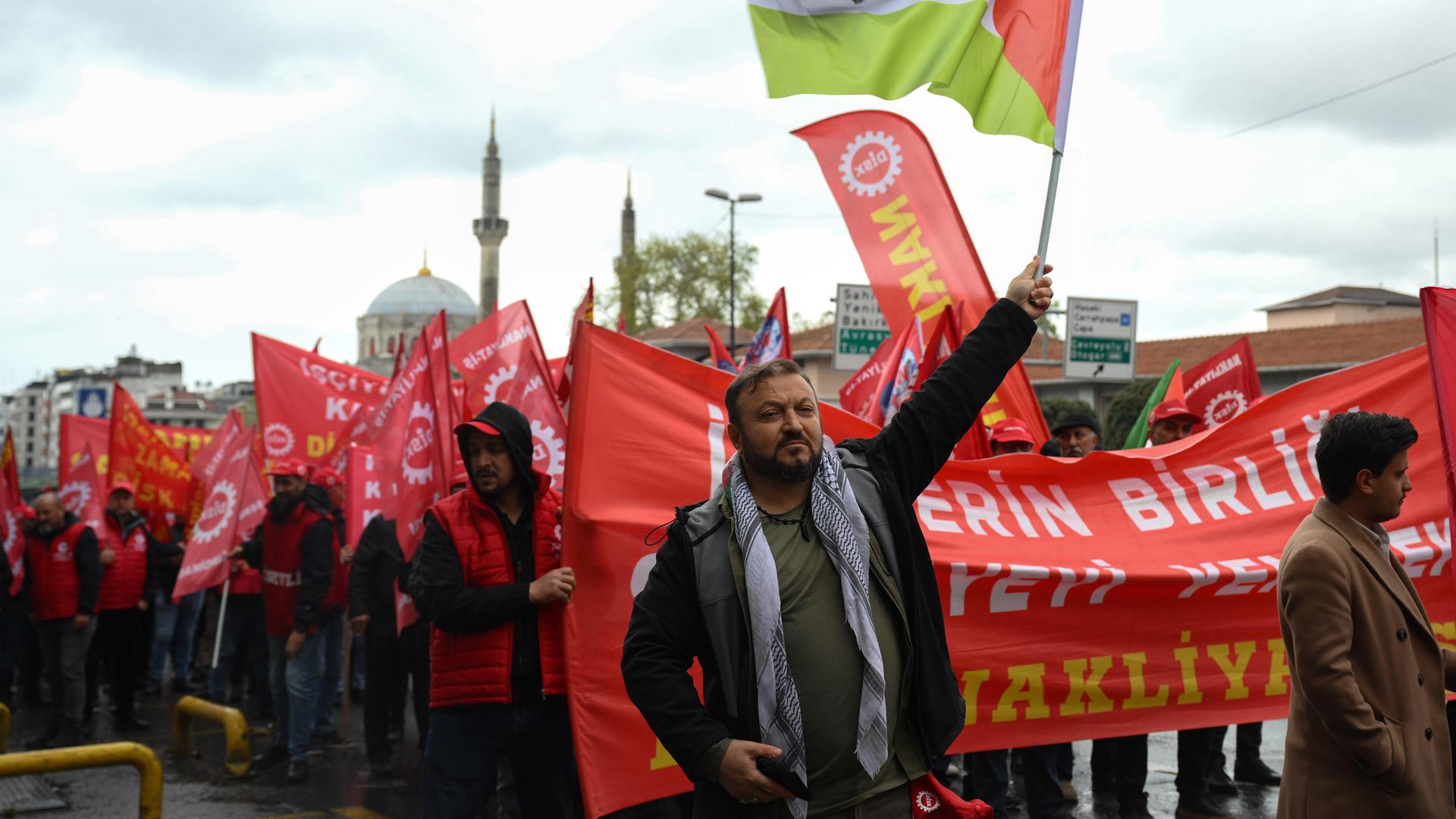 Menschen demonstrieren mit Fahnen am Tag der Arbeit in Istanbul.