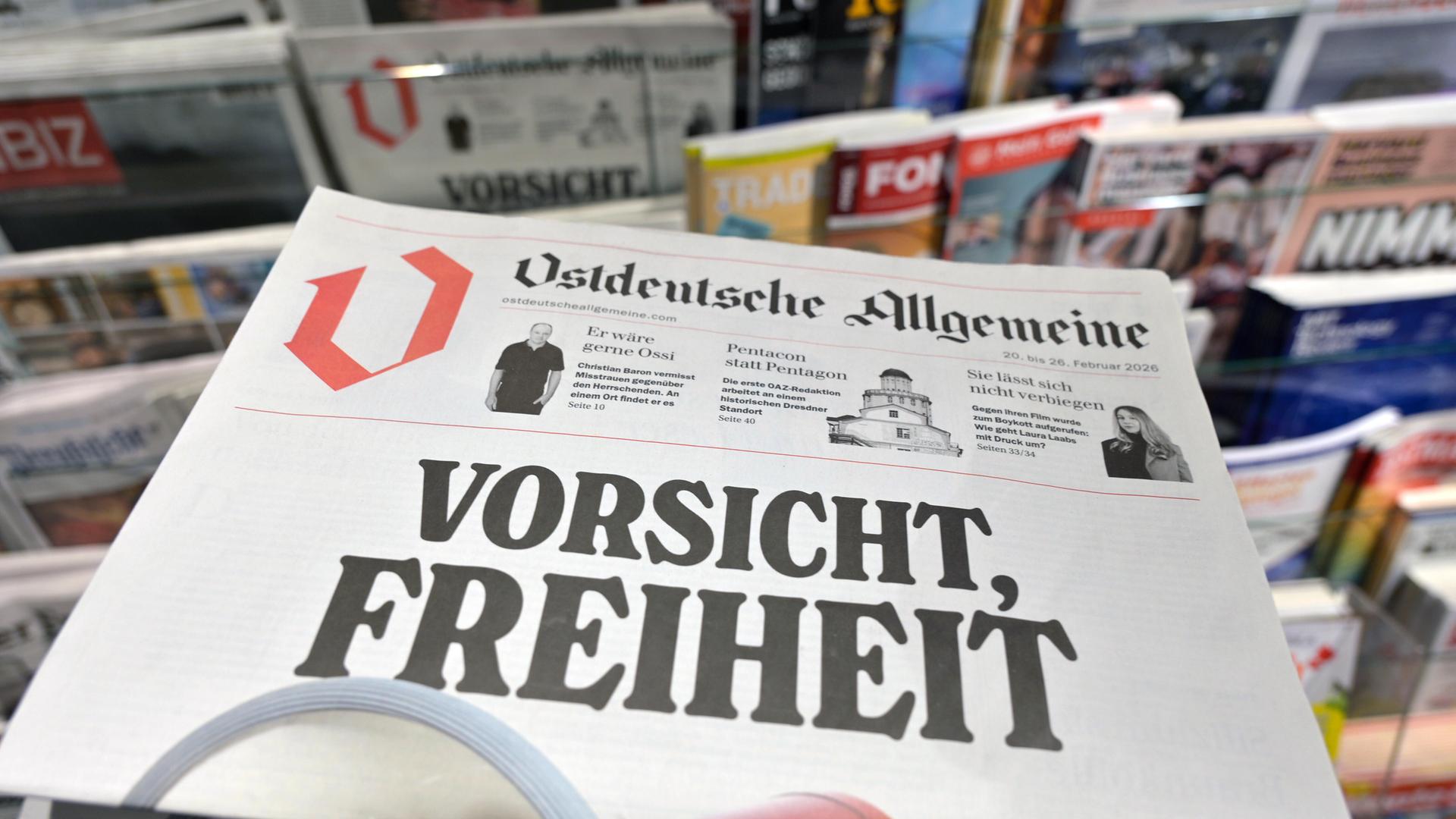 Eine Zeitung mit dem Titel "Ostdeutsche Allgemeine" und der großen Überschrift "Vorsicht, Freiheit" vor einem Regal mit anderen Zeitungen