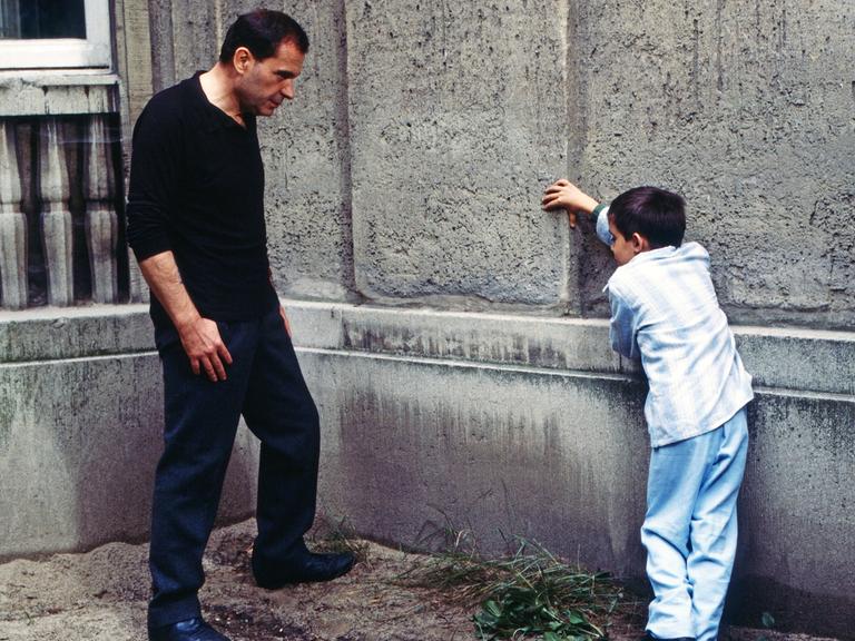 Ein Mann und ein Junge stehen sich gegenüber und lehnen an einer Wand. Eine Szene aus dem Film "Der Boxer".