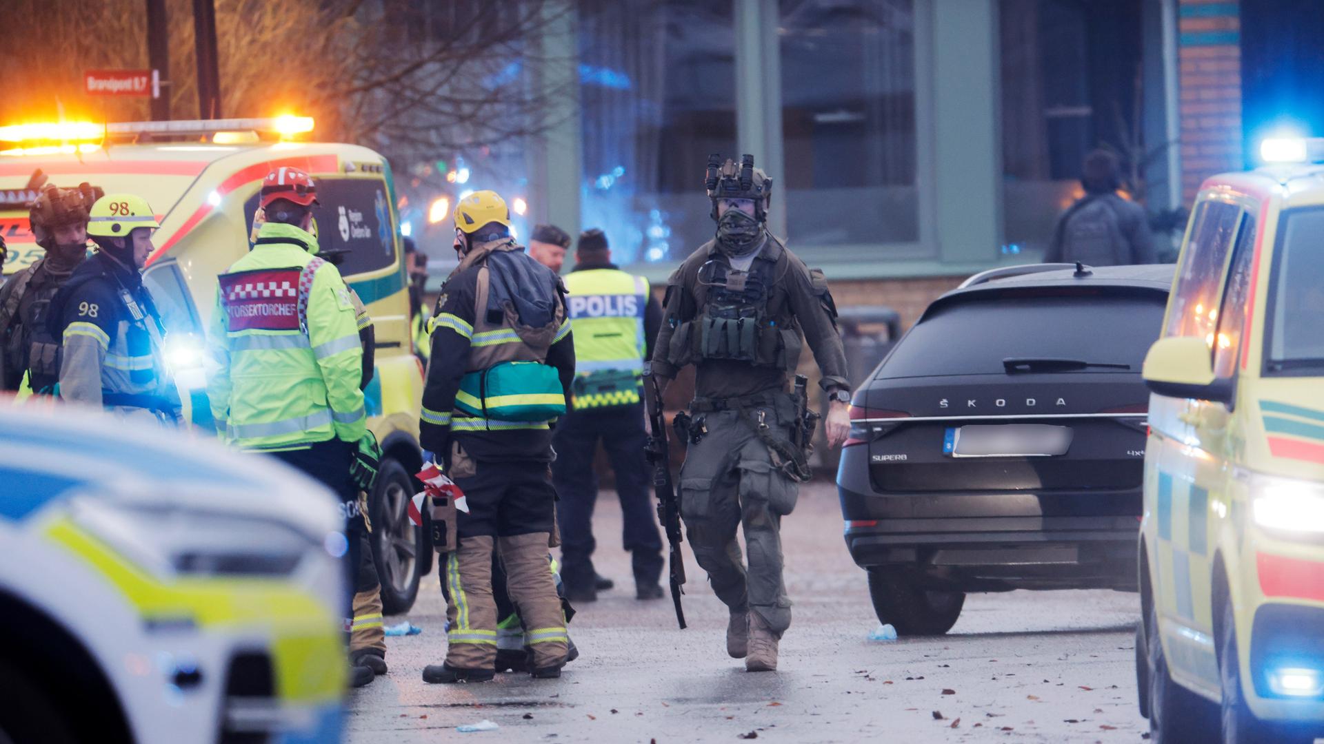 Rettungskräfte treffen an der Schule in Örebro ein. Im Vordergrund stehen Polizei-Autos.