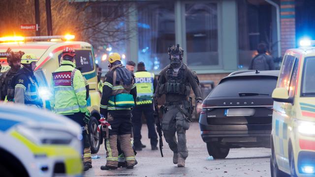 Rettungskräfte treffen an der Schule in Örebro ein. Im Vordergrund stehen Polizei-Autos.