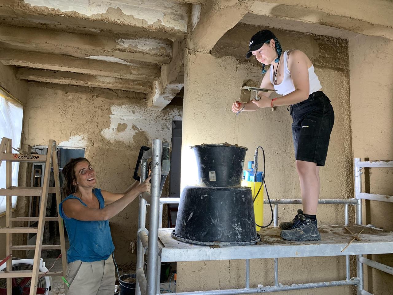 Zwei freiwillige Helferinnen des "Mobilen Teams Fluthilfe der Deutschen Stiftung Denkmalschutz" restaurieren die Innenräume eines alten Fachwerkhauses nach der Flut im Ahrtal in Rheinland-Pfalz. Eine der beiden Frauen steht auf einem Gerüst.