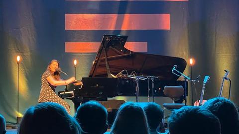 Michelle Willis sitzt am Flügel im Kammermusiksaal vor dem Streifenlogo von Deutschlandfunk.