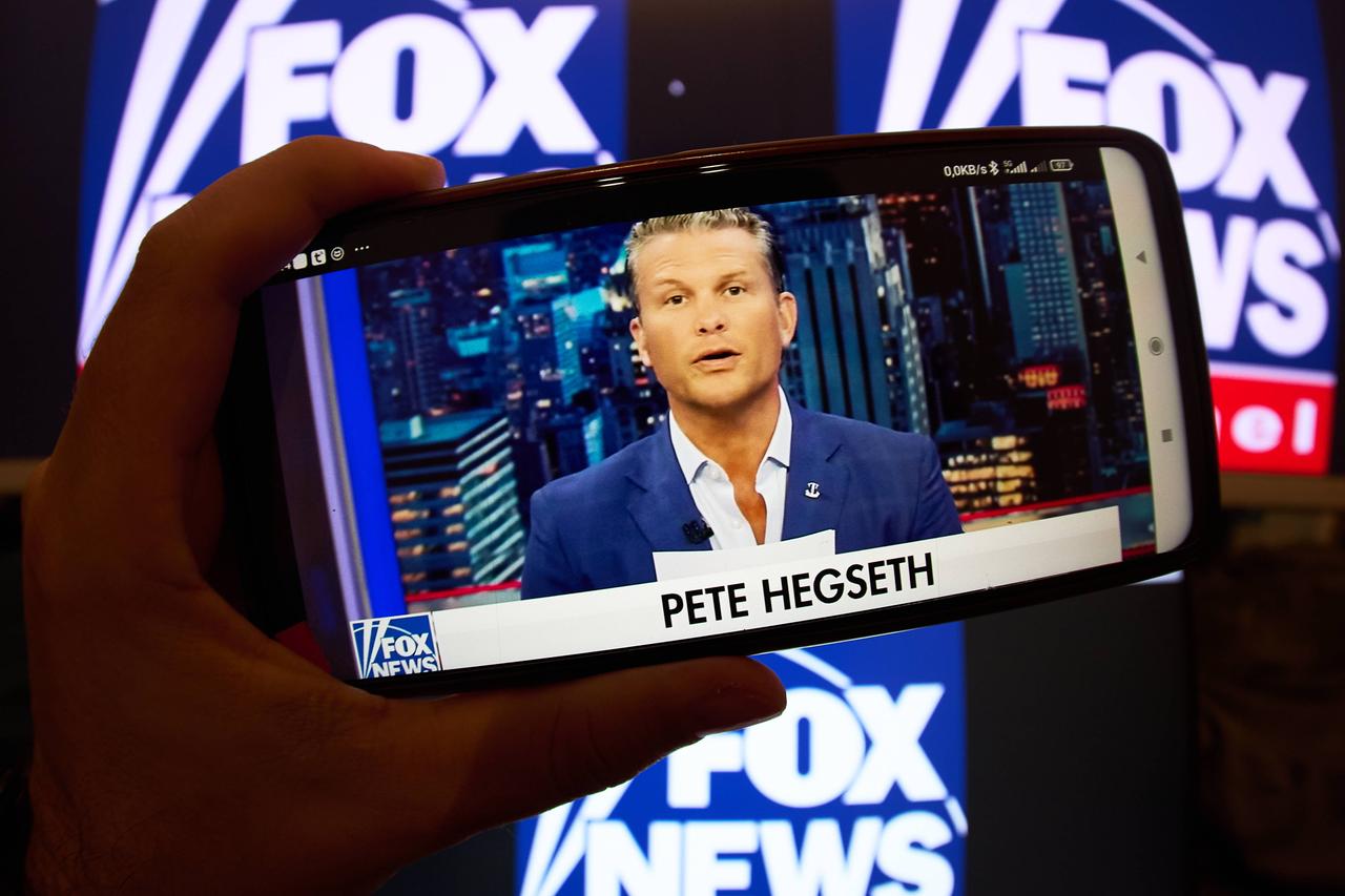 Pete Hegseth als Moderator auf Fox News, betrachtet auf einem Smartphone. 