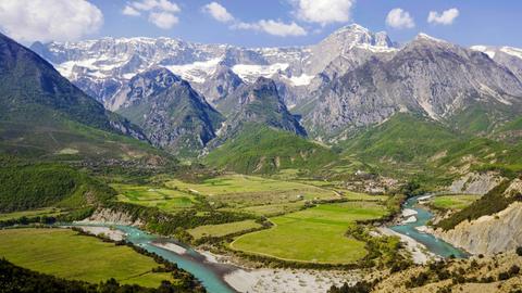 Blick auf das Tal der Vjosa im Hintergrund eine verschneite Bergkette. Die Vjosë zählt zu den wenigen größeren naturbelassenen Flüssen Europas.