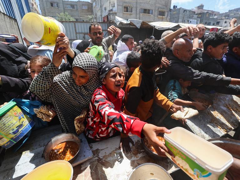 Palästinenser stehen für eine warme Mahlzeit in einer vom Welternährungsprogramm der Vereinten Nationen (WFP) betriebenen Küche im Flüchtlingslager Nuseirat im zentralen Gazastreifen an, 26. April 2025.