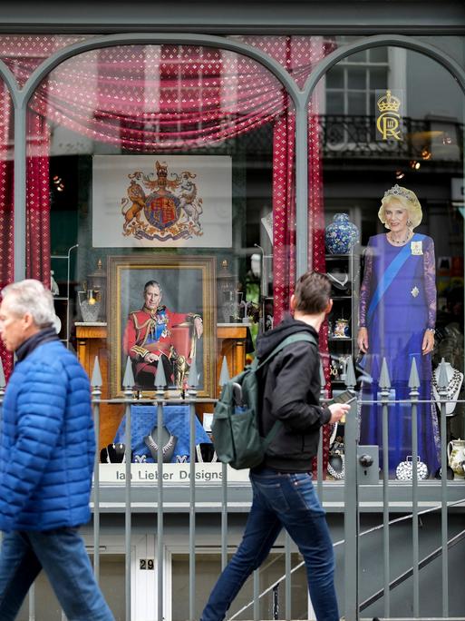 Menschen laufen an einem Schaufenster mit der Darstellung von König Charles III. in London vorbei.