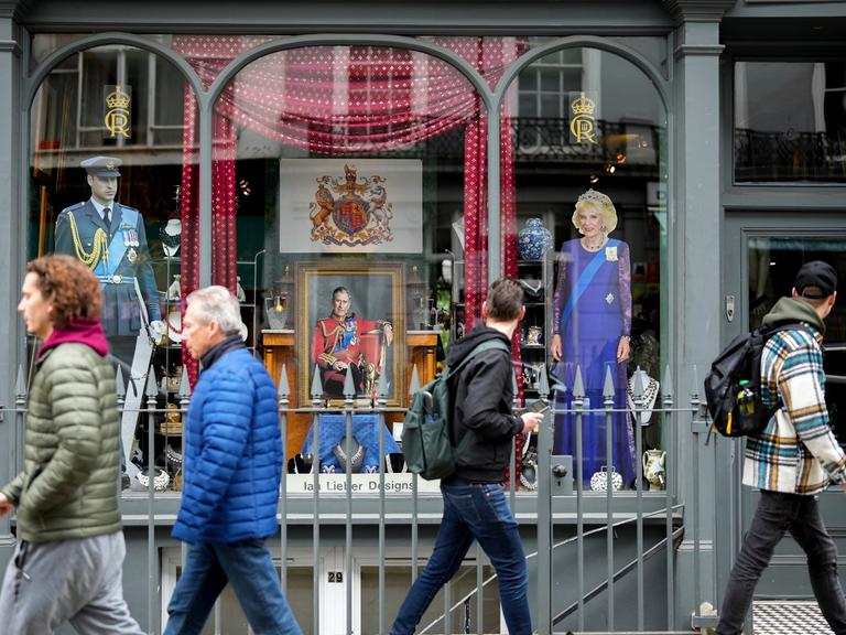 Menschen laufen an einem Schaufenster mit der Darstellung von König Charles III. in London vorbei.