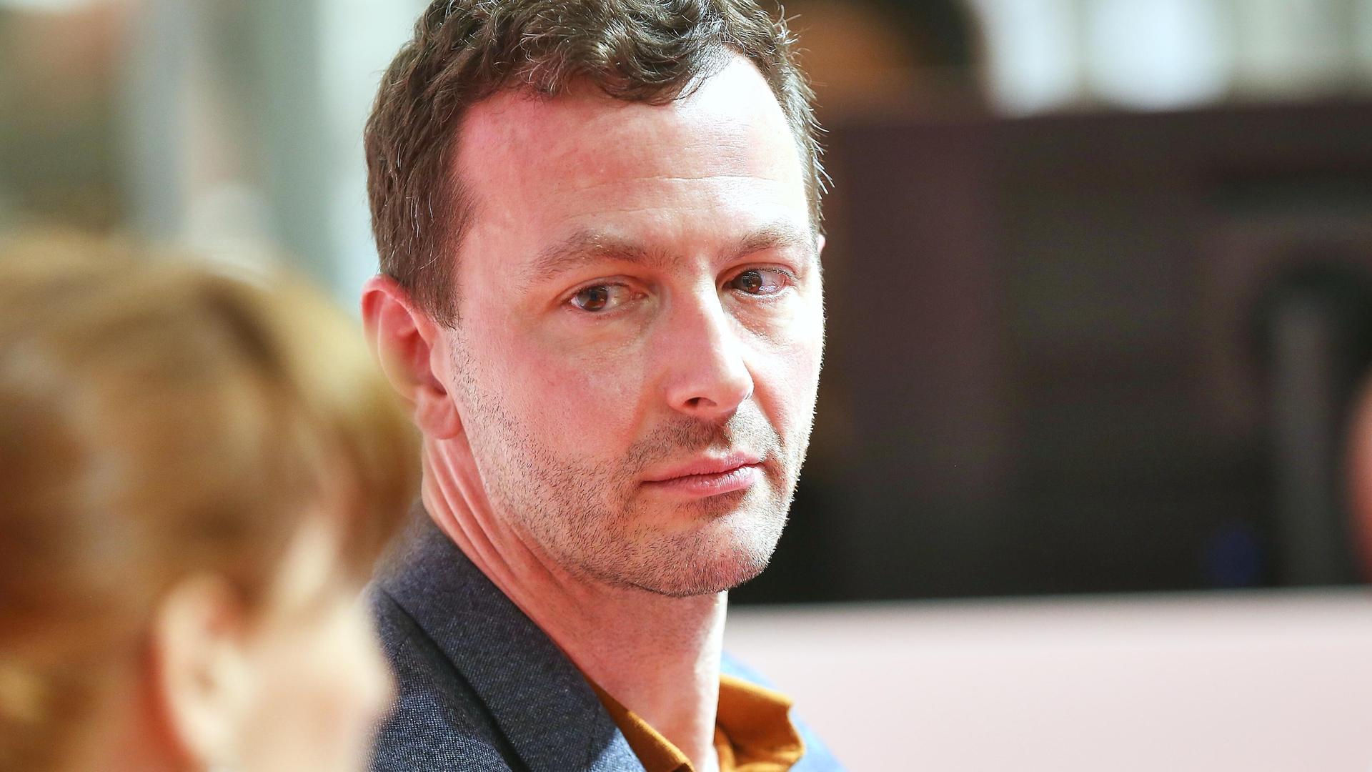 Sebastian Guggolz schaut schräg mit ernstem Gesicht über seine Schulter während er auf der Frankfurter Buchmesse 2025 ist