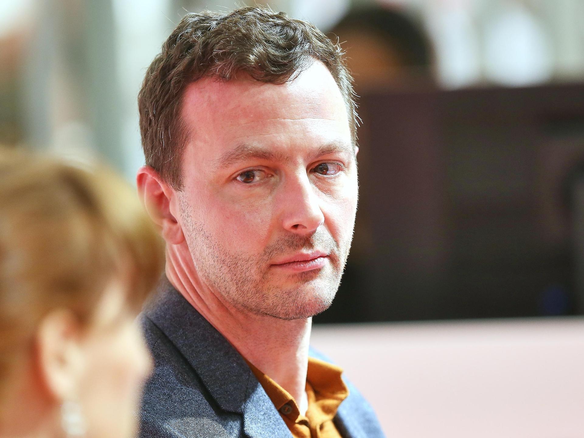 Sebastian Guggolz schaut schräg mit ernstem Gesicht über seine Schulter während er auf der Frankfurter Buchmesse 2025 ist