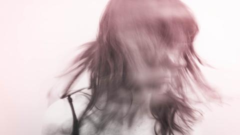 Verwischtes Bild einer Person, die den Kopf schüttelt und zur Seite schaut. Der Hintergrund ist weißlich. Die Person rötlich-violet.