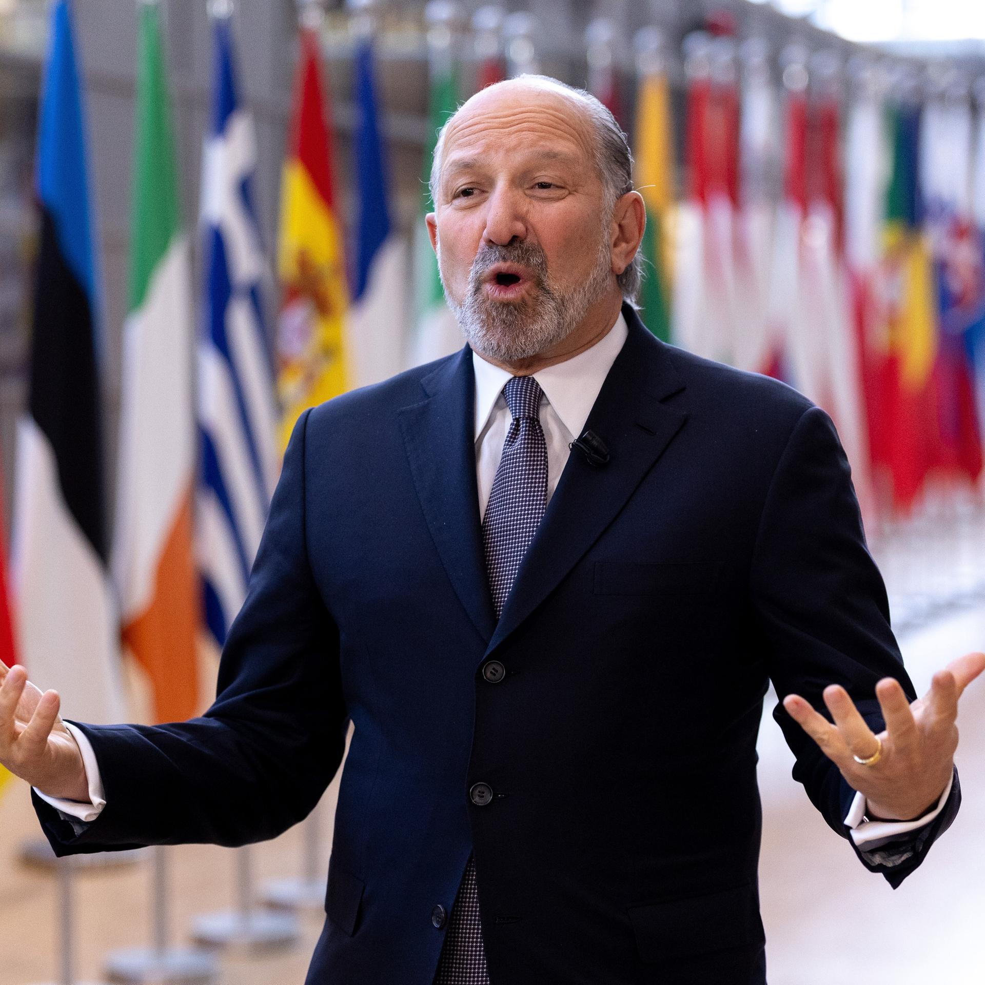 US-Handelsminister Howard Lutnick spricht und gestikuliert im Gebäude des Europäischen Rates in Brüssel. Hinter ihm sind die Flaggen der EU-Staaten. 