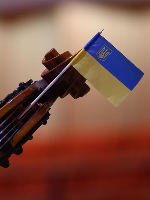 Wir sehen eine Geige, an deren Steg eine Ukraine-Flagge befestigt wurde. 