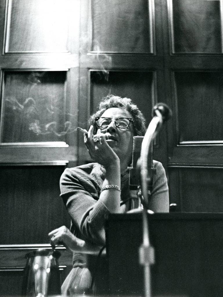 Filmstill aus "Hannah Arendt - Die Pflicht zum Ungehorsam" in dem Hannah Arendt Zigarette rauchend sitzend an einem Tisch lehnt. 