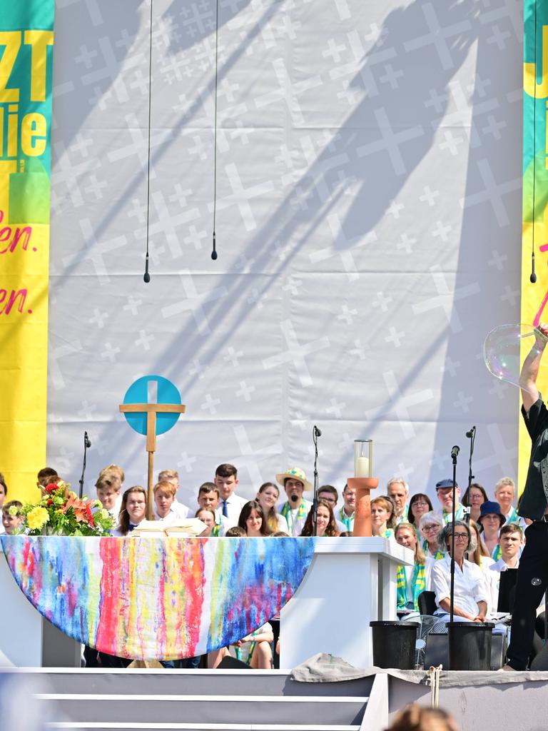 Abschlussgottesdienst des Evangelischen Kirchentags in Nürnberg. Ein Seifenblasenkünstler steht vor einem Altar auf der Bühne. Im Hintergrund sind zwei Banner mit der Aufschrift "jetzt ist die Zeit. Hoffen. Machen"