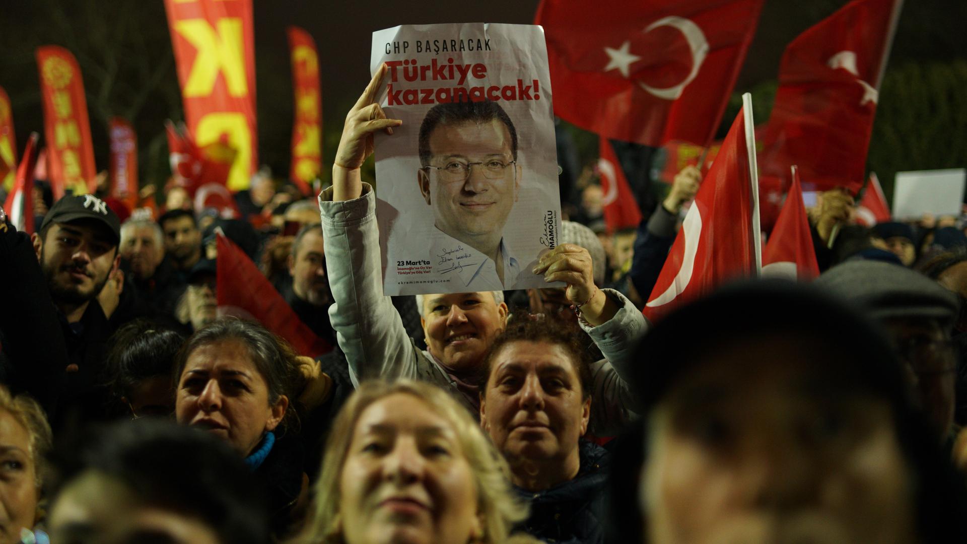 Eine Kundgebung in Istanbul: Eine Person hält ein Plakat mit dem Bild des Istanbuler Bürgermeisters Ekrem Imamoglu in der Hand.