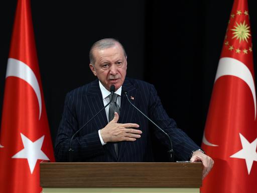 Der türkische Präsident Recep Tayyip Erdoğan an einem Rednerpult, links und rechts stehen türkische Flaggen.