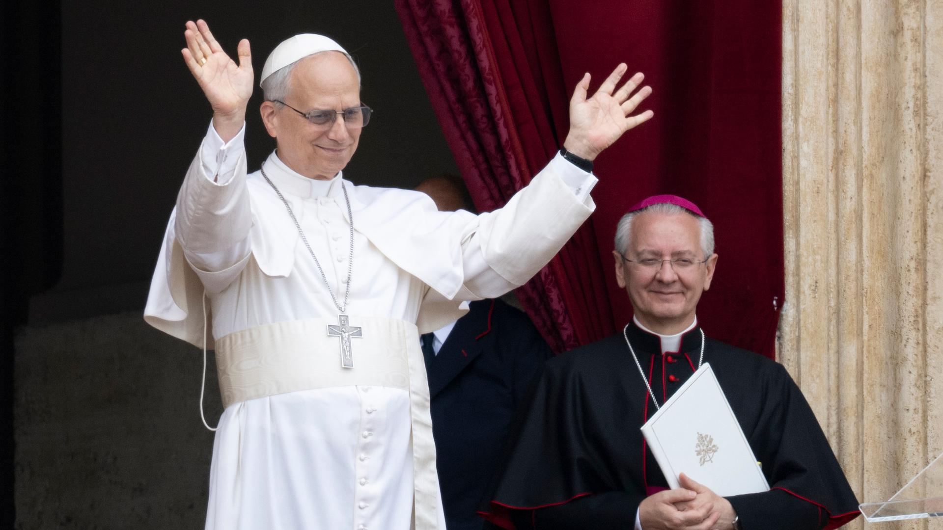 Papst Leo steht auf dem Balkon des Petersdoms bei seinem ersten Sonntagssegen. Er trägt ein weißes Gewand und hat die Arme erhoben. Papst Leo steht auf dem Balkon des Petersdoms bei seinem ersten Sonntagssegen. Er trägt ein weißes Gewand und hat die Arme erhoben.