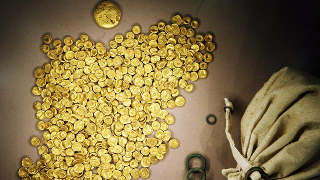 Gold-Münzen liegen auf einem Haufen. Daneben liegt ein Sack aus Stoff.