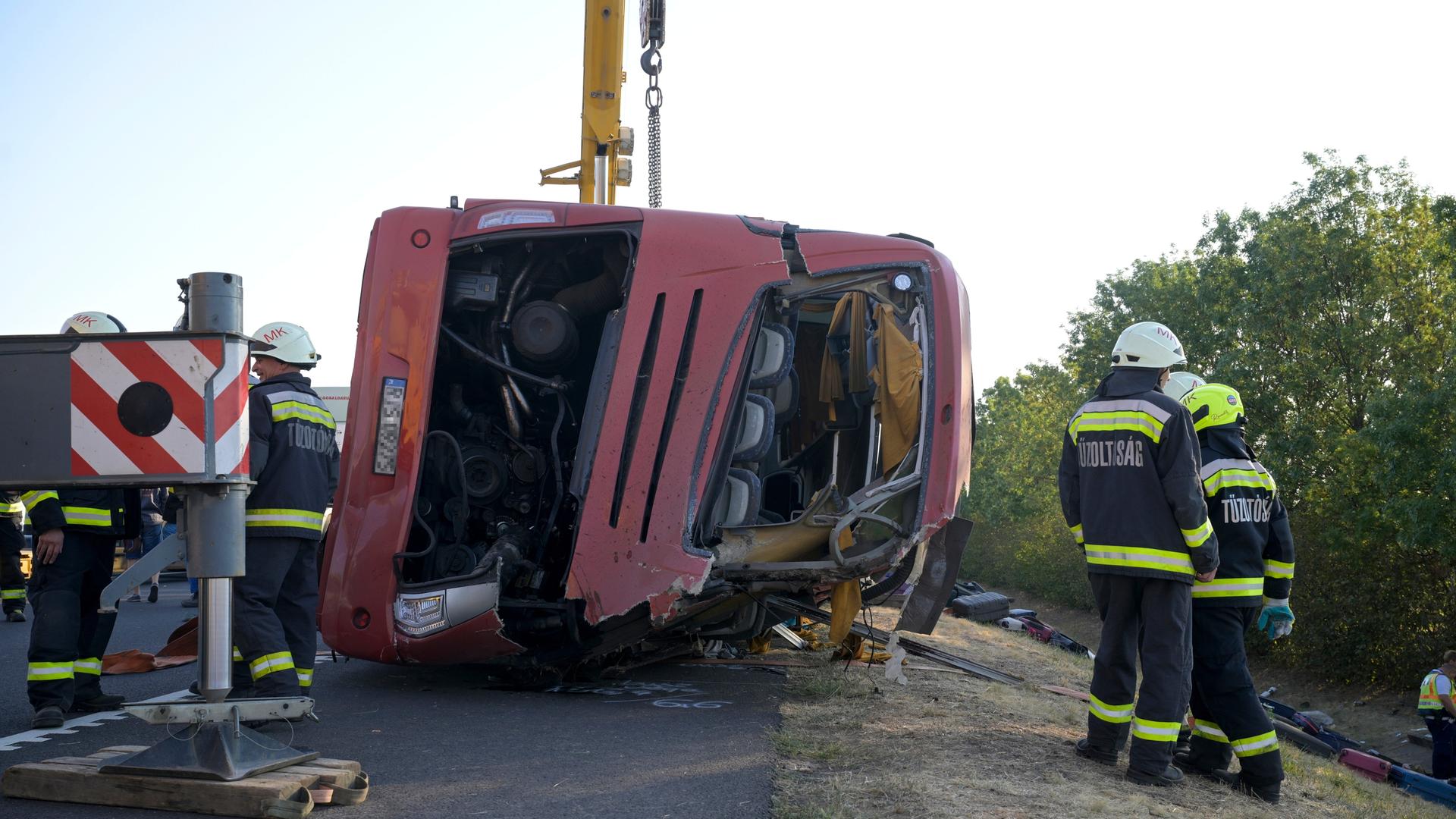 Der schwer beschädigte und eingedrückte Bus liegt auf der Seite am oberen Rand des Abhangs. Dahinter ein Kran, daneben Rettungskräfte. Der schwer beschädigte und eingedrückte Bus liegt auf der Seite am oberen Rand des Abhangs. Dahinter ein Kran, daneben Rettungskräfte.