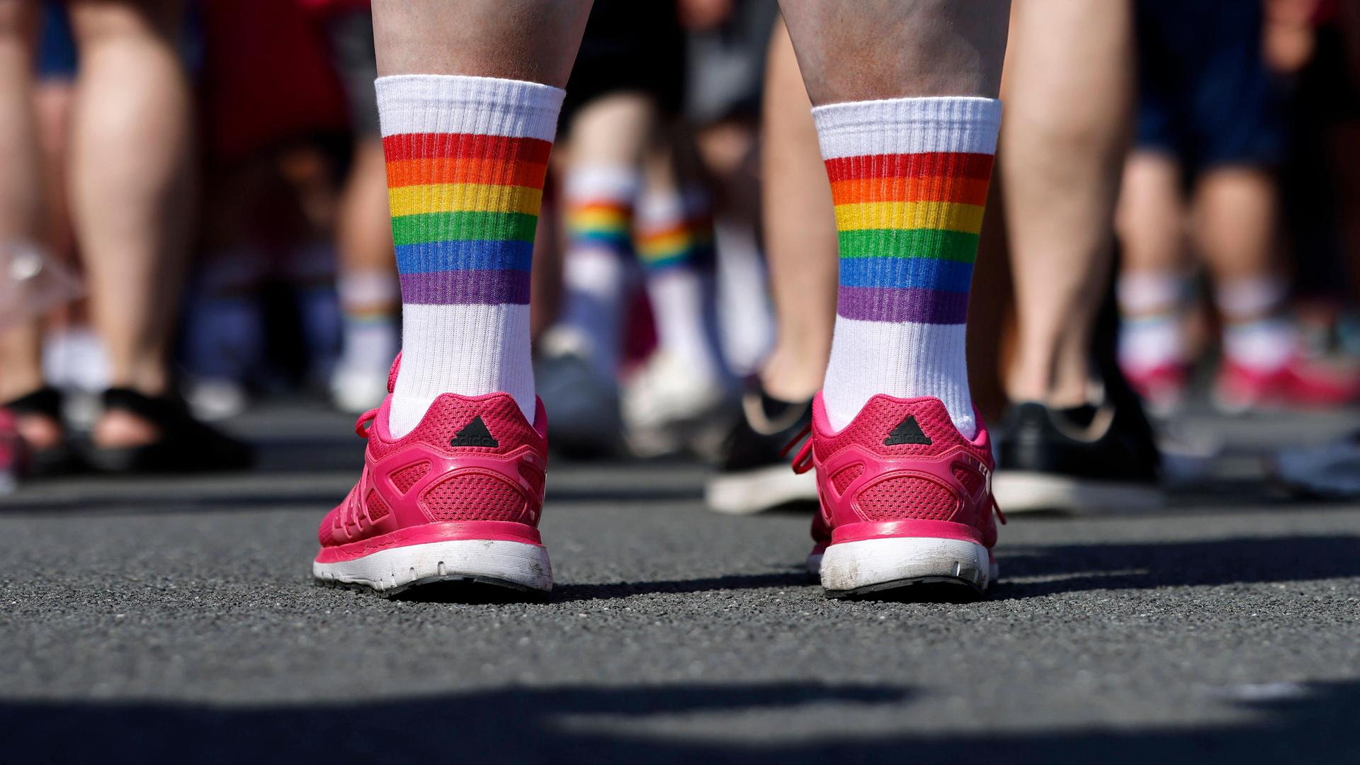 Das Bild zeigt die Unterschenkel eines Teilnehmers mit roten Schuhen und Regenbogen-Socken.