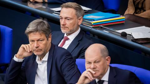 Bundeskanzler Olaf Scholz (SPD), Christian Lindner (FDP), Bundesminister der Finanzen, und Robert Habeck (Bündnis 90/Die Grünen), Bundesminister für Wirtschaft und Klimaschutz, verfolgen von der Regierungsbank aus die Debatte im Deutschen Bundestag.