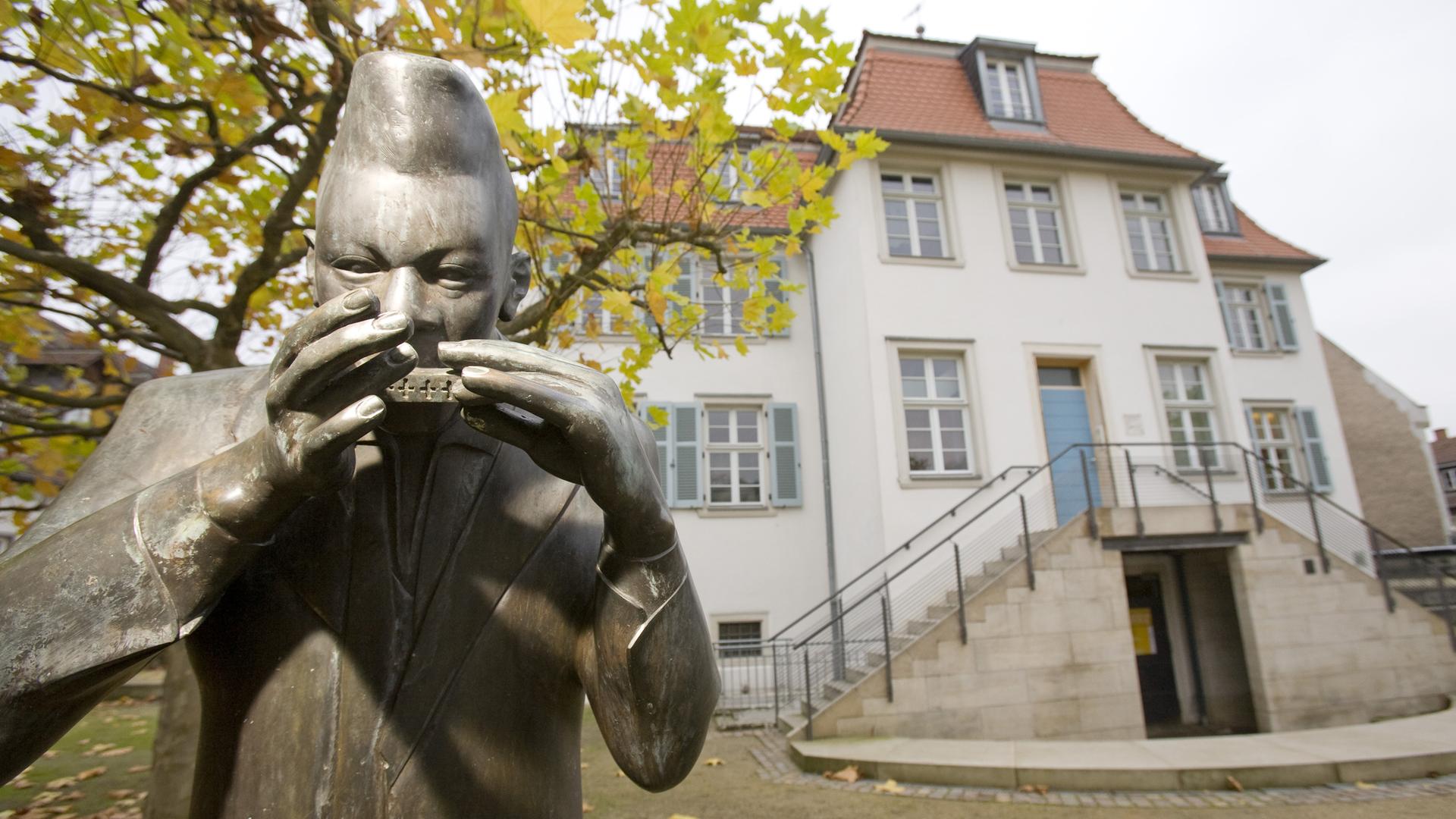 Blick auf das historische Bessunger Kavaliershaus in Darmstadt mit der Bronzeplastik eines Mundharmonikaspielers, wo heute das Jazzinstitut Darmstadt untergebracht ist.