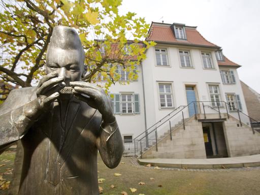 Blick auf das historische Bessunger Kavaliershaus in Darmstadt mit der Bronzeplastik eines Mundharmonikaspielers, wo heute das Jazzinstitut Darmstadt untergebracht ist.