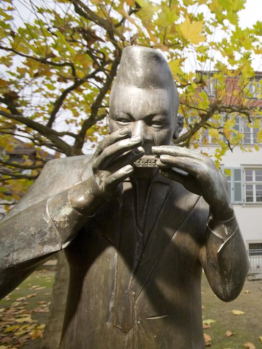 Blick auf das historische Bessunger Kavaliershaus in Darmstadt mit der Bronzeplastik eines Mundharmonikaspielers, wo heute das Jazzinstitut Darmstadt untergebracht ist.