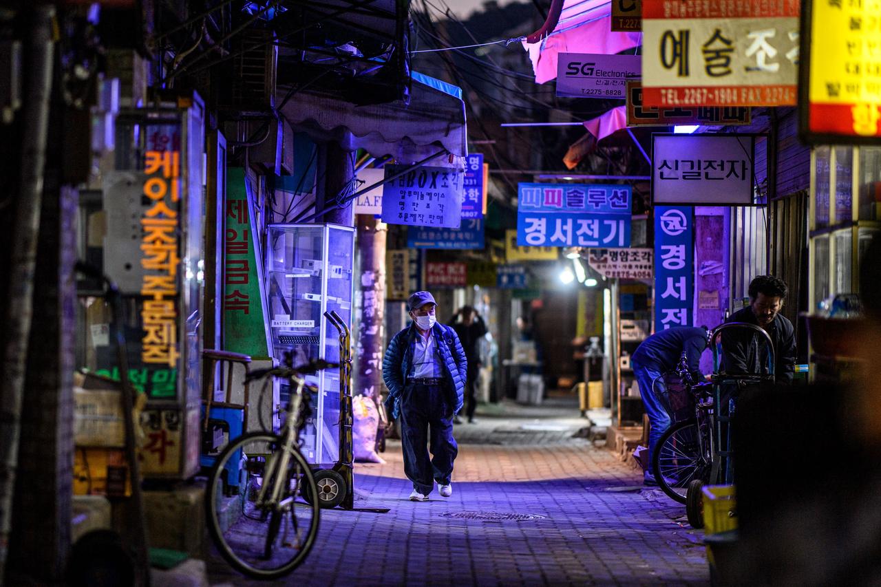 Ein älterer Mann läuft durch eine erleuchtete Straße in Seoul.